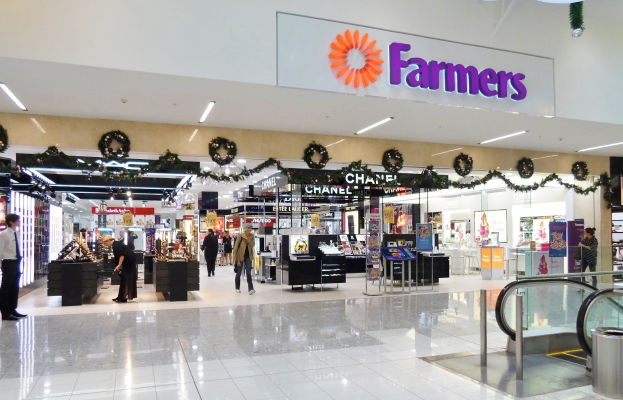 Das Innere eines Bauernmarkts in einem Einkaufszentrum, mit Menschen, die herumlaufen, Geschäften mit Namensschildern, Deko-Artikeln, Lichtern und einem Müllimer.