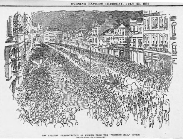 Schwarze und weiße Zeichnung einer Menge, die eine Straße entlang geht, flankiert von Gebäuden, mit Text oben und unten, der "Die Unionistendemonstration aus der Sicht des Western Mail Office" lautet.