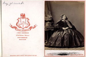 Eine Frau, die auf einem Stuhl neben einer Säule sitzt, mit einem Stempel, einer Unterschrift und Notizen auf der linken Seite.