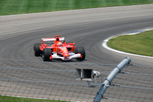 Ein Fahrzeug fährt auf einer Straße mit Gras und einem Maschendrahtzaun auf der Seite.