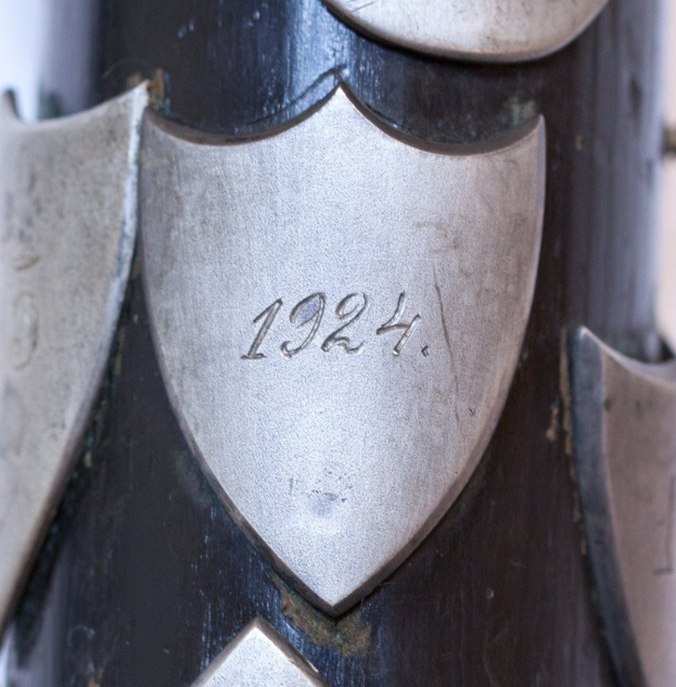 Nahaufnahme eines metallischen Gegenstands mit einer eingravierten Zahl, der wie eine Schusswaffe aussieht.