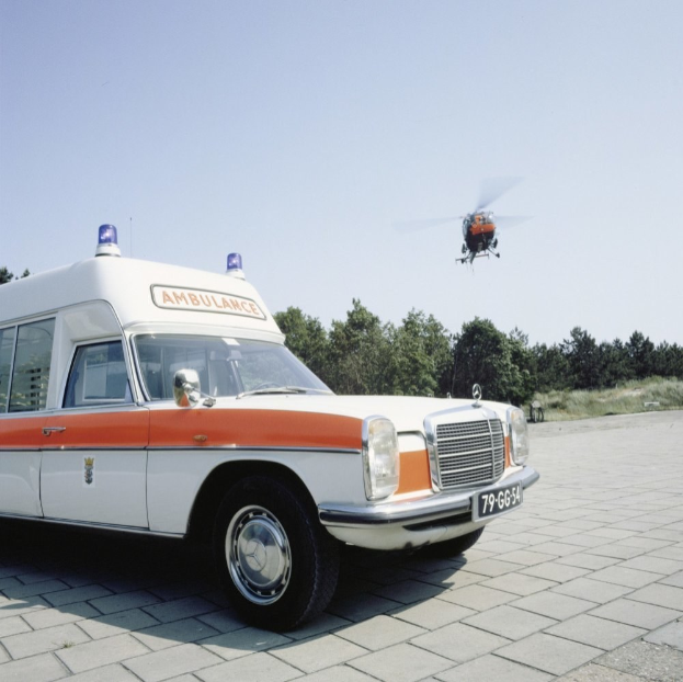 Ambulanz vor Hubschrauber mit Bäumen und einem klaren blauen Himmel im Hintergrund geparkt.