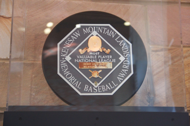 Eine schwarze Plakette an einem Gebäude trägt die Aufschrift "Mountain Lands Memorial Baseball Award" mit einer Wand im Hintergrund.