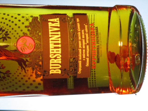 Eine Flasche Olivenöl mit einer goldbraunen Flüssigkeit steht auf einem Tisch und zeigt ein sichtbares Etikett.