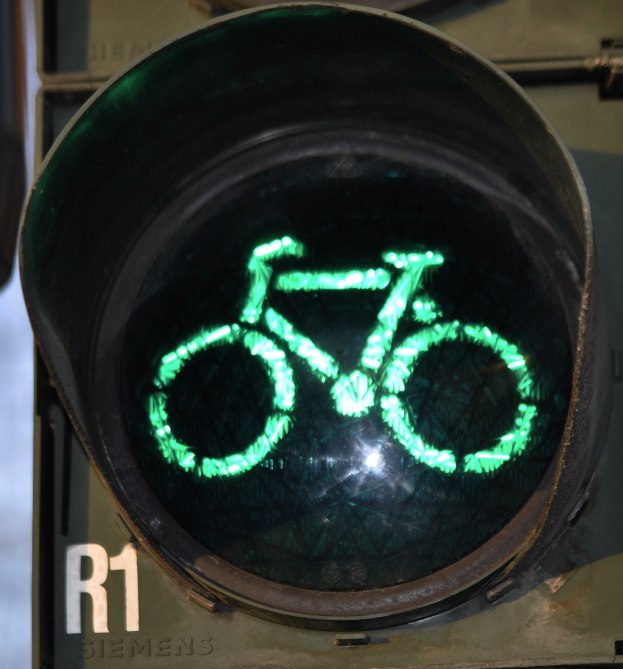 Grünes Verkehrslicht mit Fahrradsymbol, das an einer Wand leuchtet.