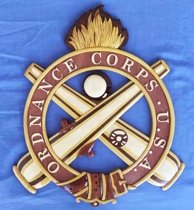 Holzschild mit "Ordnance Corps" in schwarzer Schrift, auf blauem Tuch montiert, mit einem weißen Stern auf marineblauem Hintergrund und goldener Umrandung.