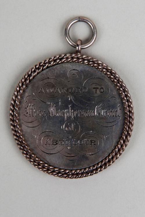 Silberne Medaille mit schwarzem Text "Ausgezeichnet an den Metropolitan Council" an einer Schnur, mit einem dekorativen Rand.
