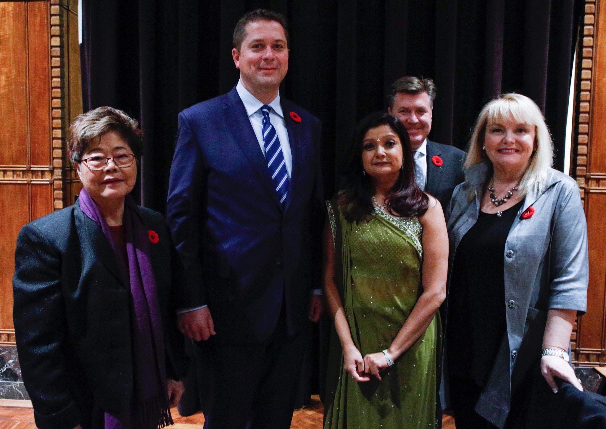 Gruppe von Menschen vor einem schwarzen Vorhang mit einer hölzernen Wand im Hintergrund, die scheinbar Mitglieder der Freien Demokraten bei einer Versammlung sind.