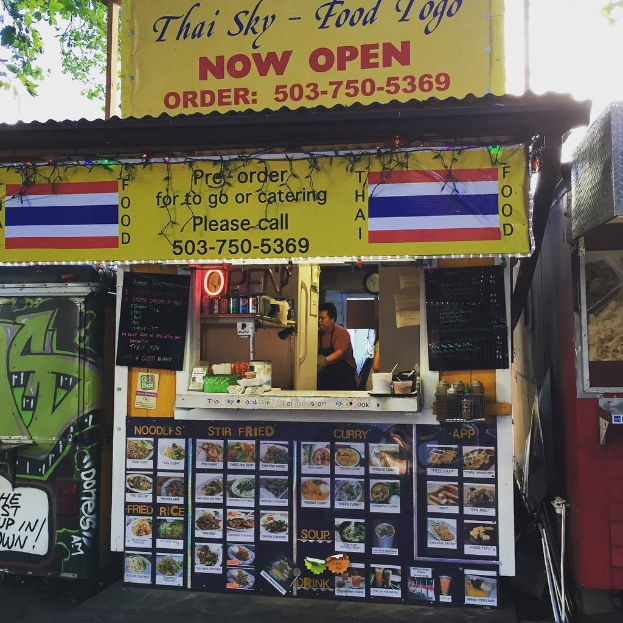 Läden, Getränkedosen, Speisekarten, eine Uhr, Gewürze in Plastikbehältern, Kondimente, Werbetafeln, Namensschilder und Himmel.