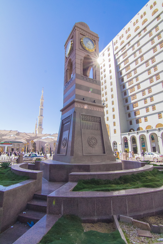 Eine zentrale Struktur mit einer Uhr und einem großen Gebäude rechts.