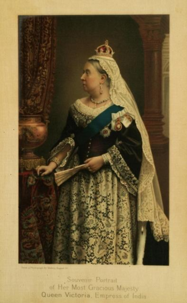 Schwarzes und weißes Foto von Queen Victoria, Kaiserin von Indien, in prunkvoller Kleidung mit einer Krone, vor einer Säule und einem Vorhang stehend, mit der Beschriftung "Souvenir-Porträt Ihrer allergnädigsten Majestät" unten.