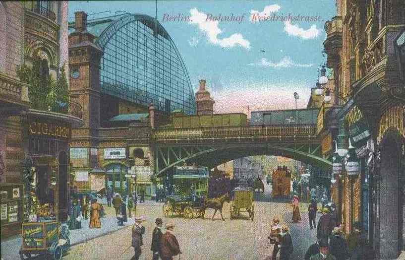 Alte Ansichtskarte einer belebten Straßenkreuzung in Berlin, Deutschland, mit Passanten, Pferdefuhrwerken, Gebäuden, Laternenpfählen, einer Brücke und einem bewölkten Himmel mit Text oben.
