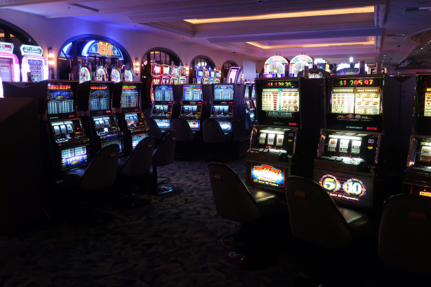 Reihe von Spielautomaten zum Verkauf in einem Casino mit Stühlen und Deckenbeleuchtung.