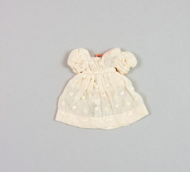 Ein kleines weißes Kleid mit rundem Halsausschnitt, kurzen Ärmeln und einem knielangen Saum, das ein zartes Muster auf leichtem, luftigem Stoff aufweist, der leicht gekräuselt erscheint.