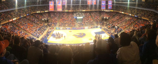 Gro├če Halle mit Zuschauern bei einem Basketballspiel, mit einem Spielfeld, sitzenden Fans in den R├Ąngen und ├ťberkopfbeleuchtung und Bannern.
