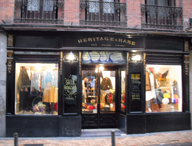 Erbschafts- und seltenes Boutique-Geschäft in Madrid mit Schaufensterpuppen, Kleidern und Beleuchtung, das über einer Straße zu sehen ist.