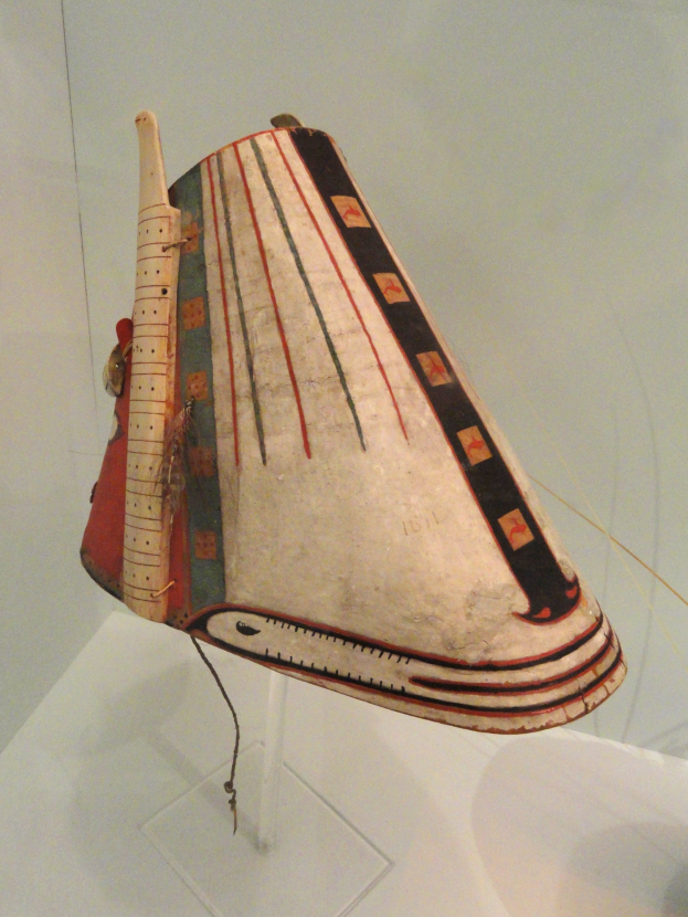 Eine hölzerne Balalaika in einer Glasvitrine auf einer weißen Oberfläche mit einer Wand im Hintergrund.