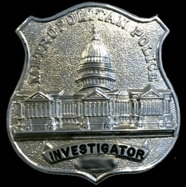 Ein silbern glänzendes Polizeiabzeichen mit der Aufschrift "Ermittler" vor einem weißen Hintergrund.