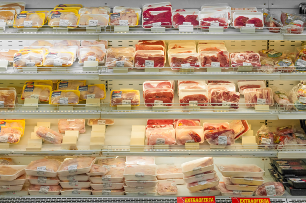 Ein gut organisierter Gemüsemarkt mit verschiedenen Fleischsorten, die ordentlich auf Regalen angeordnet sind und Preisschilder an den Ständen haben.